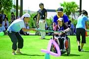 Photograph : A pair with wheelchair man is showing the “Universal Sports” that they are created.